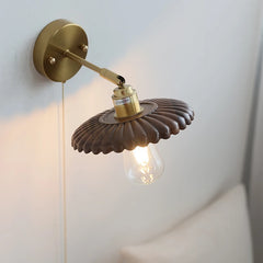 Wall-mounted lamp with decorative shade and exposed bulb on a light background