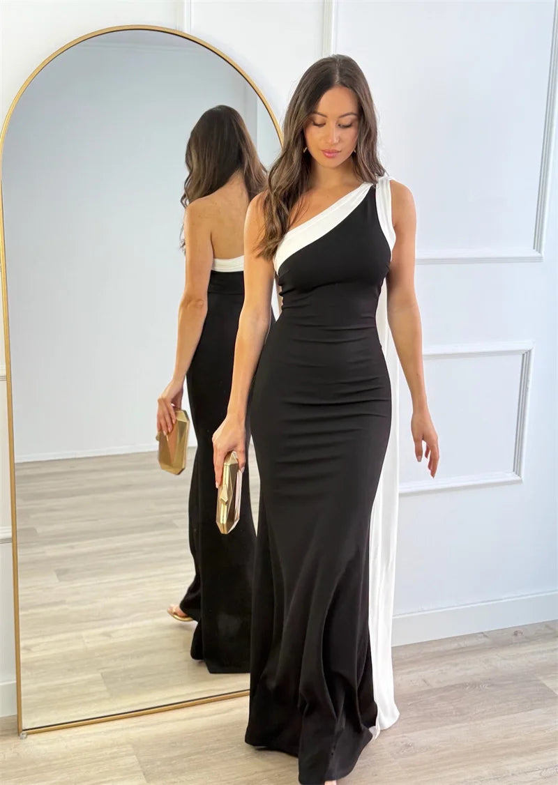 Woman in a black and white dress standing in front of a mirror.