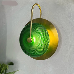 Close-up of a gold wall sconce, highlighting the intricate metalwork and the vibrant green glass shade. A