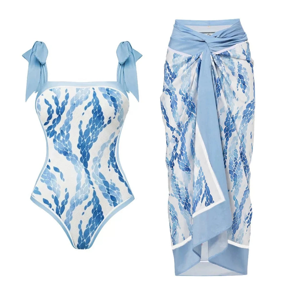 One-piece swimsuit with blue scale print and tie straps, paired with a wrap-style skirt with matching print.