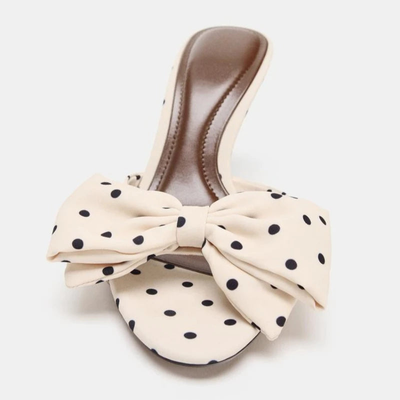 White sandal with a large polka dot bow on a white background