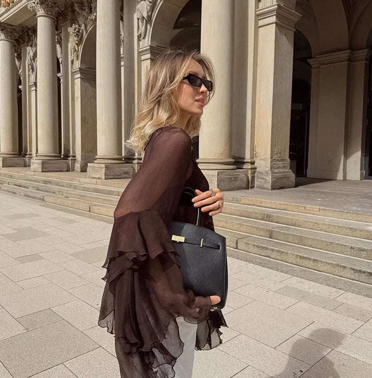Woman holding a black handbag in front of classical architecture