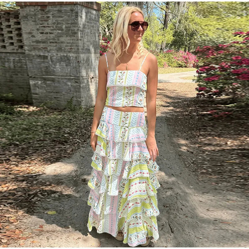 Woman wearing a printed ruffled crop top and cascading ruffle maxi skirt set in a garden setting