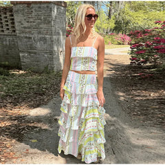 Woman wearing a printed ruffled crop top and cascading ruffle maxi skirt set in a garden setting