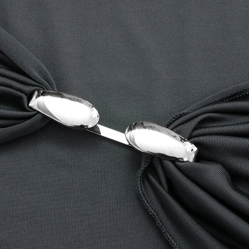 Close-up of a black garment with a bow and silver clasp on a dark background
