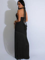 Woman wearing a black halter neck dress with pleated skirt against a white background