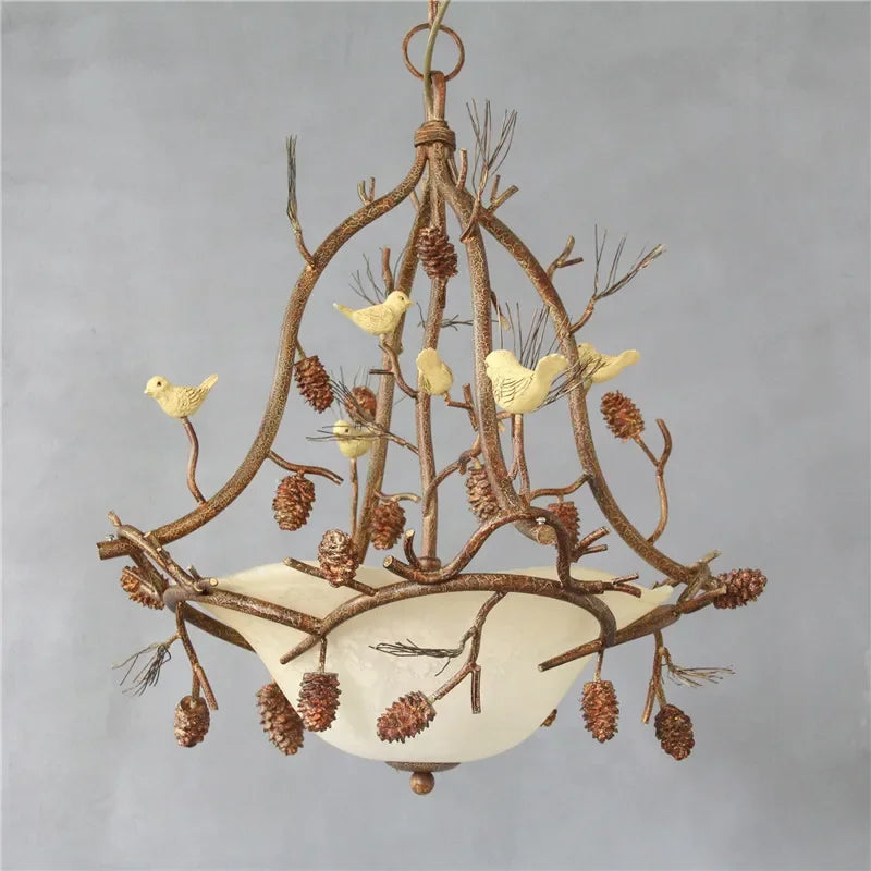 Decorative chandelier with branches, birds, and pinecones on a gray background