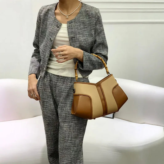 Woman holding a bamboo handle colorblock leather handbag with a tweed suit