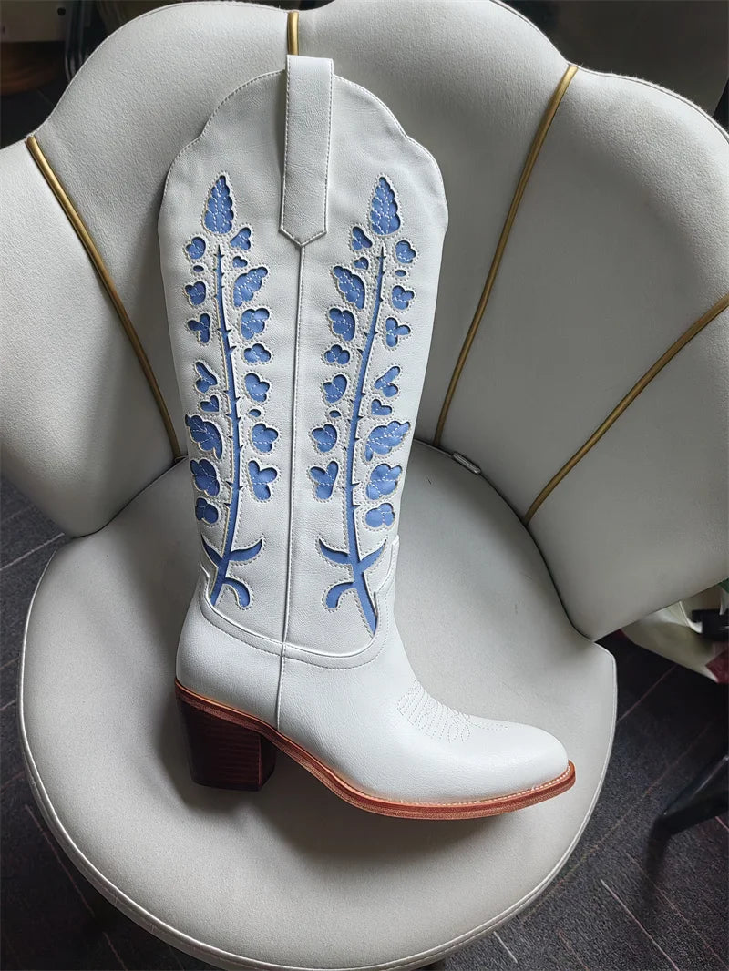 White cowboy boot with blue floral embroidery on a white surface