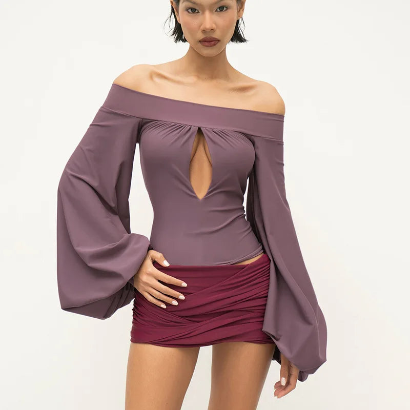 Woman wearing a purple off-shoulder top with long sleeves and a matching skirt on a white background