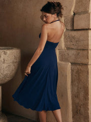 Woman in a blue dress standing against a stone wall.