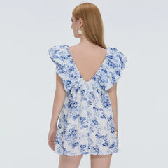 Woman wearing a blue floral dress with a plain background