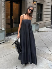 Woman in a long black dress standing on a city street.