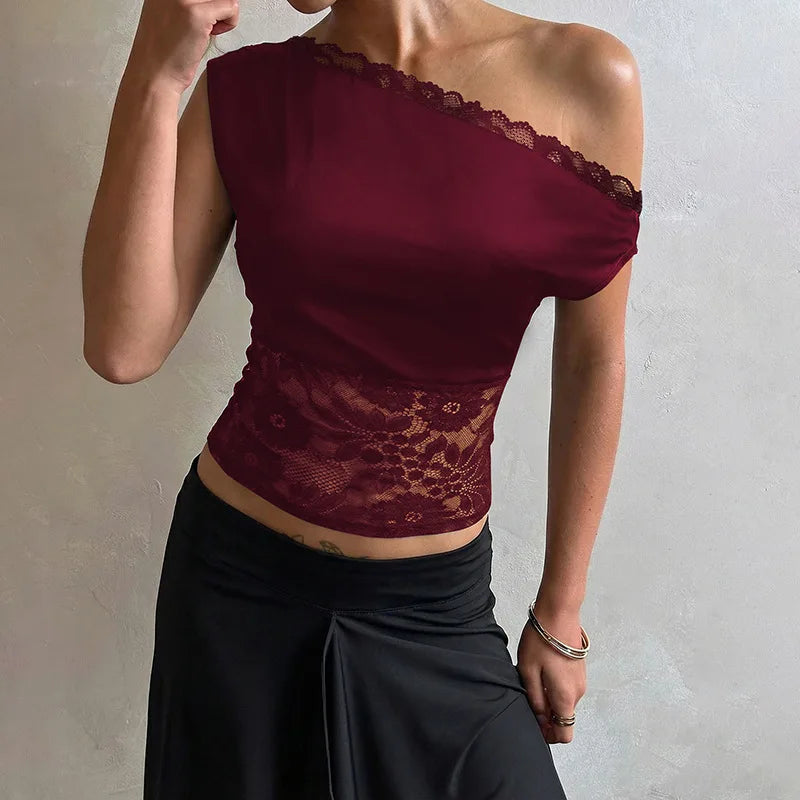 Woman wearing a burgundy one-shoulder top with lace details against a neutral background
