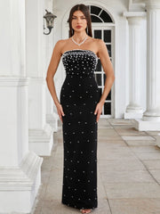 Woman wearing a black strapless dress with white embellishments in front of a classical building.