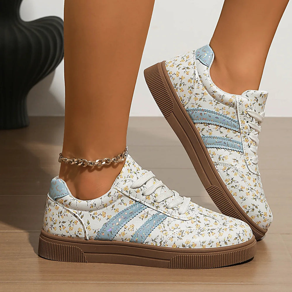 Floral print lace-up sneakers on feet with an anklet.