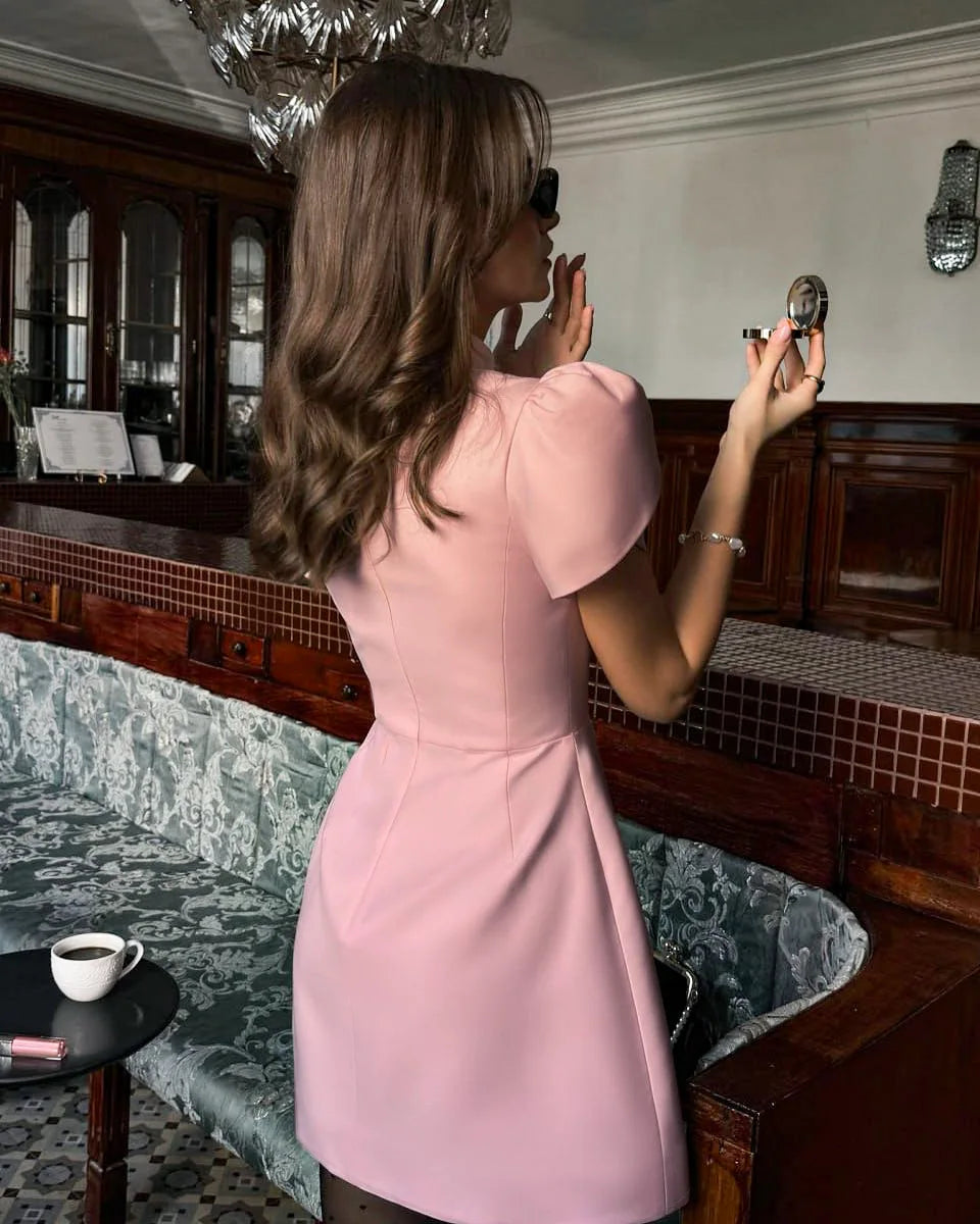 Woman in a pink dress taking a mirror selfie in an elegant room.