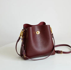 Brown leather handbag with gold accents on a white surface