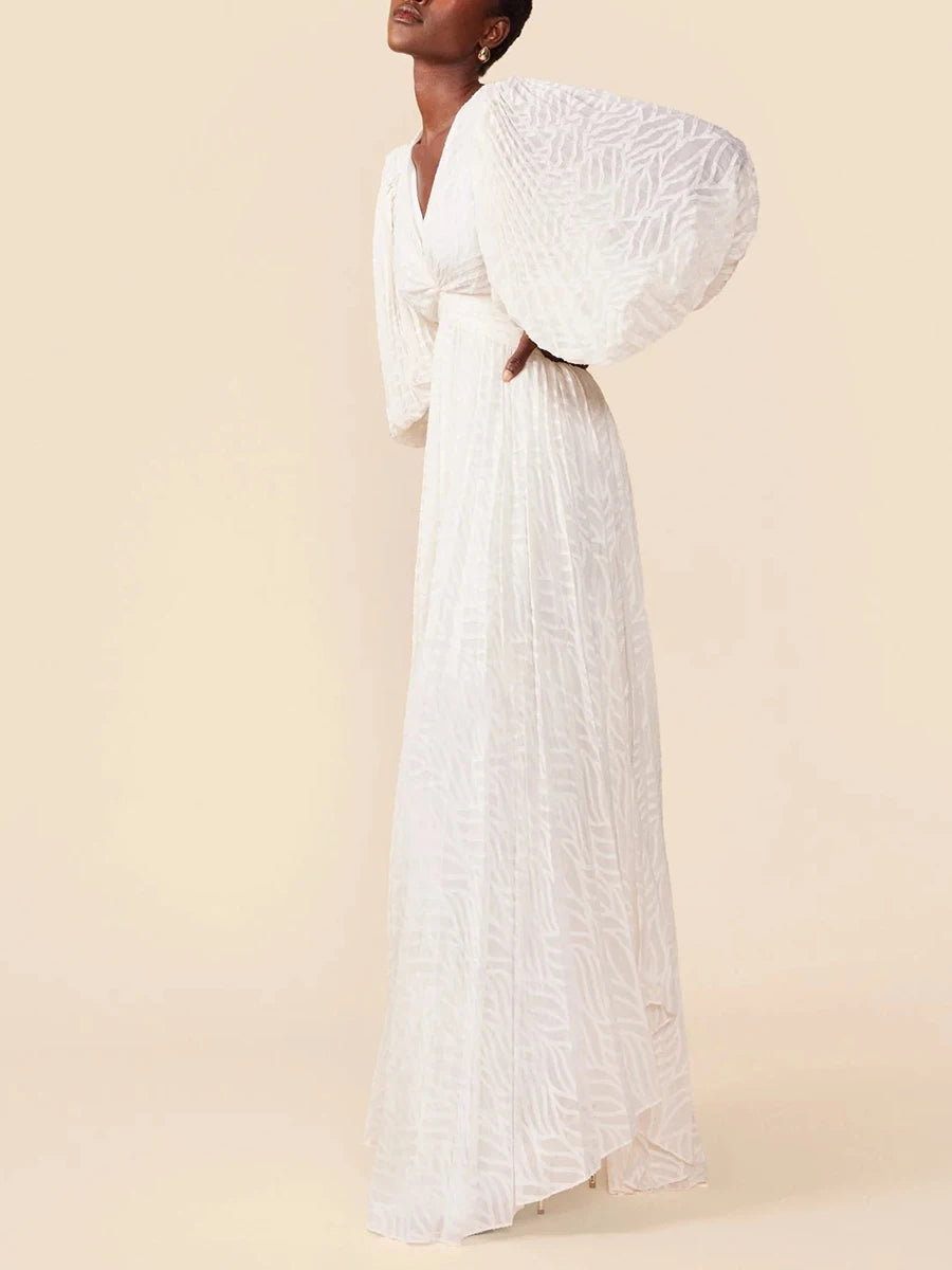 Woman wearing a white dress with textured sleeves against a beige background