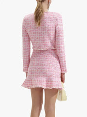 Person wearing a pink tweed outfit with a white background