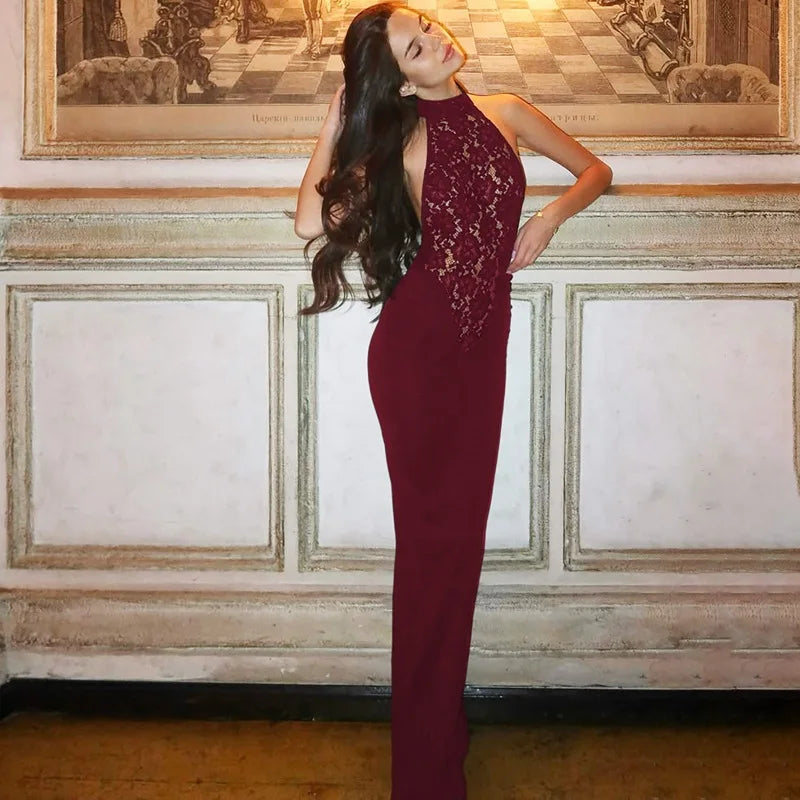 Woman in a burgundy evening gown standing in an elegant room with decorative wall art.