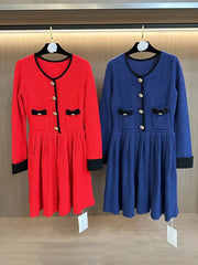 Red and blue dresses on hangers against a wooden wall.