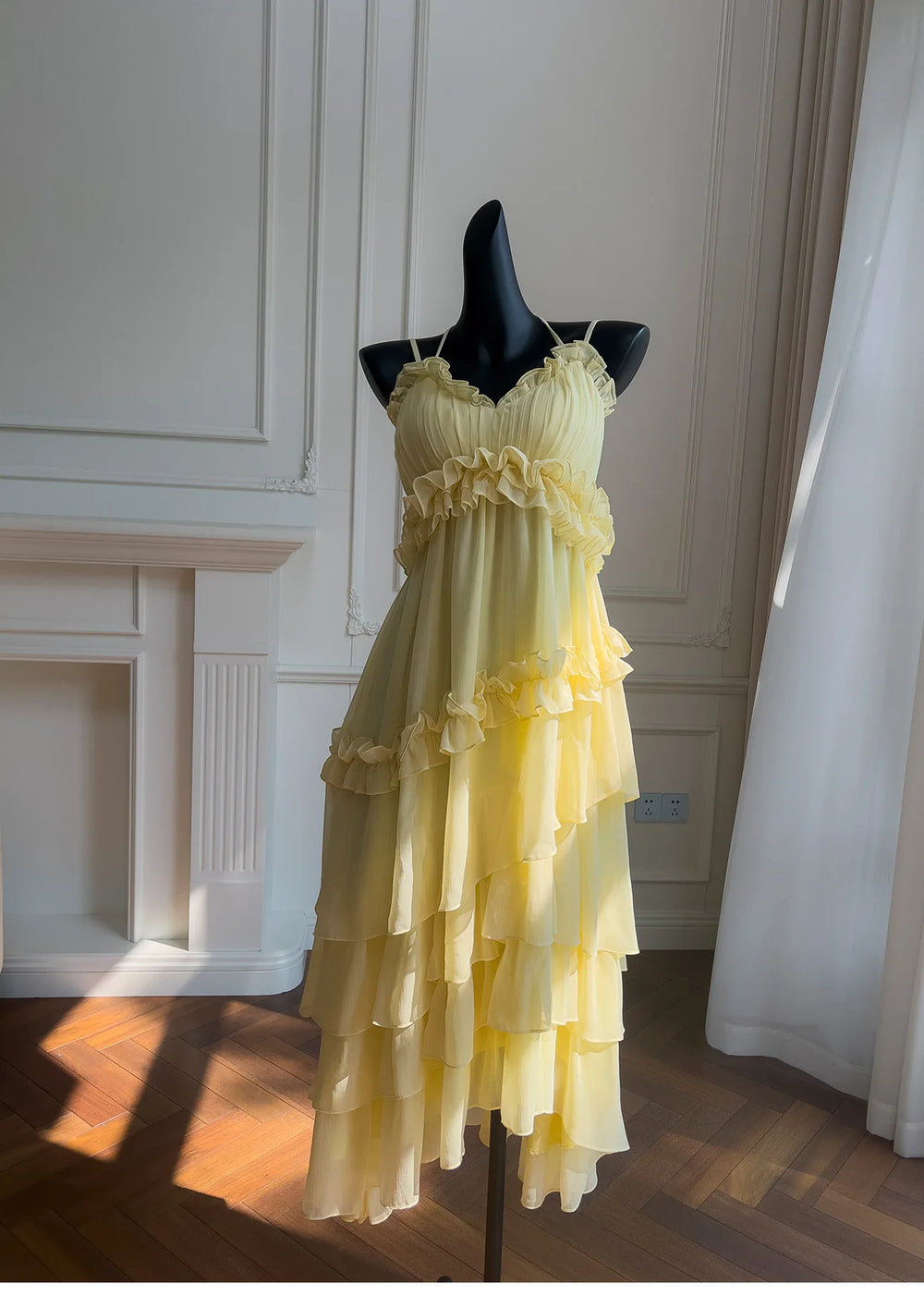 Yellow ruffled chiffon maxi dress on a black mannequin, front view with dramatic lighting.