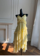 Yellow ruffled chiffon maxi dress on a black mannequin, front view with dramatic lighting.