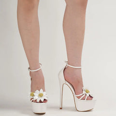 White high-heeled shoes with floral details on a neutral background