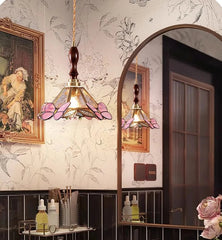 Decorative bathroom with floral wallpaper, stained glass pendant light, and framed artwork.