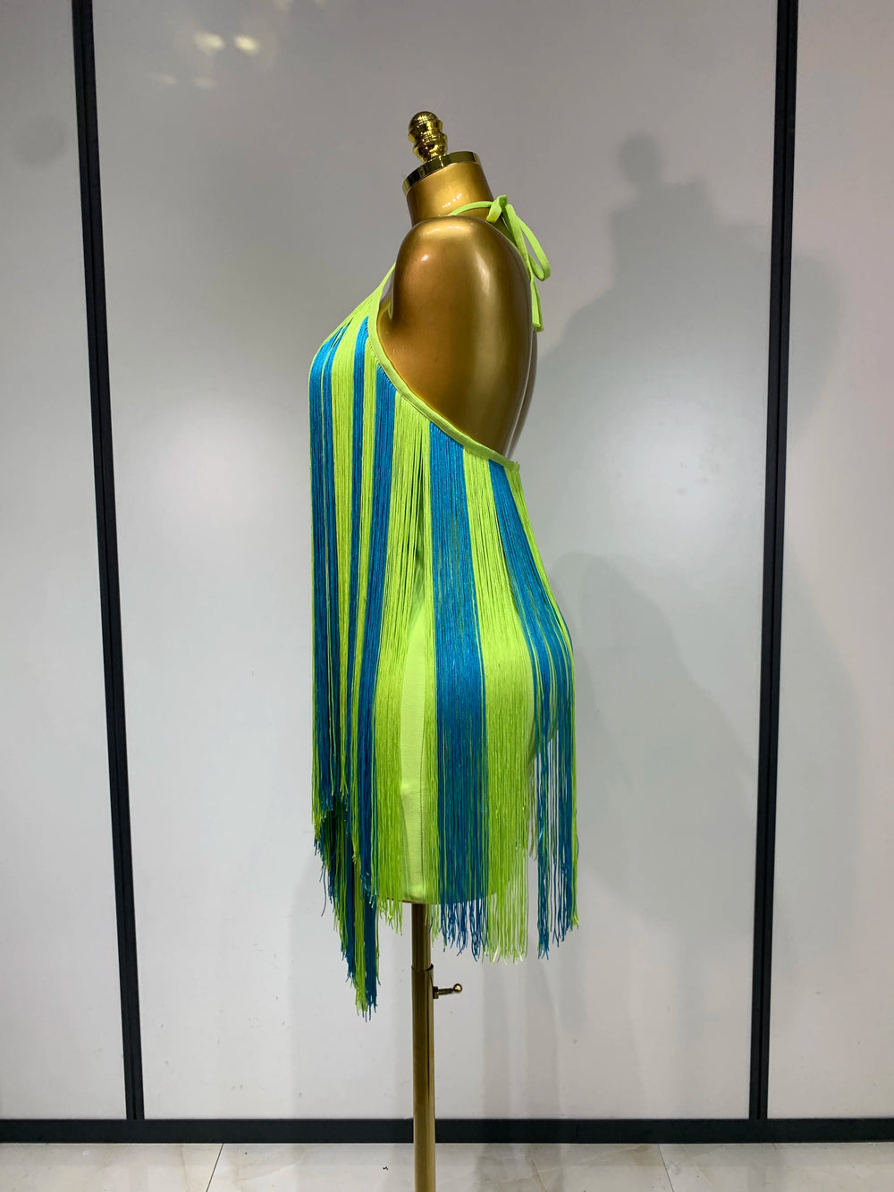 Back view of lime green and blue alternating fringe halter mini dress
