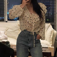Person wearing a beige polka dot blouse and blue jeans in a living room setting.