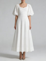 White dress with puffed sleeves on a plain background