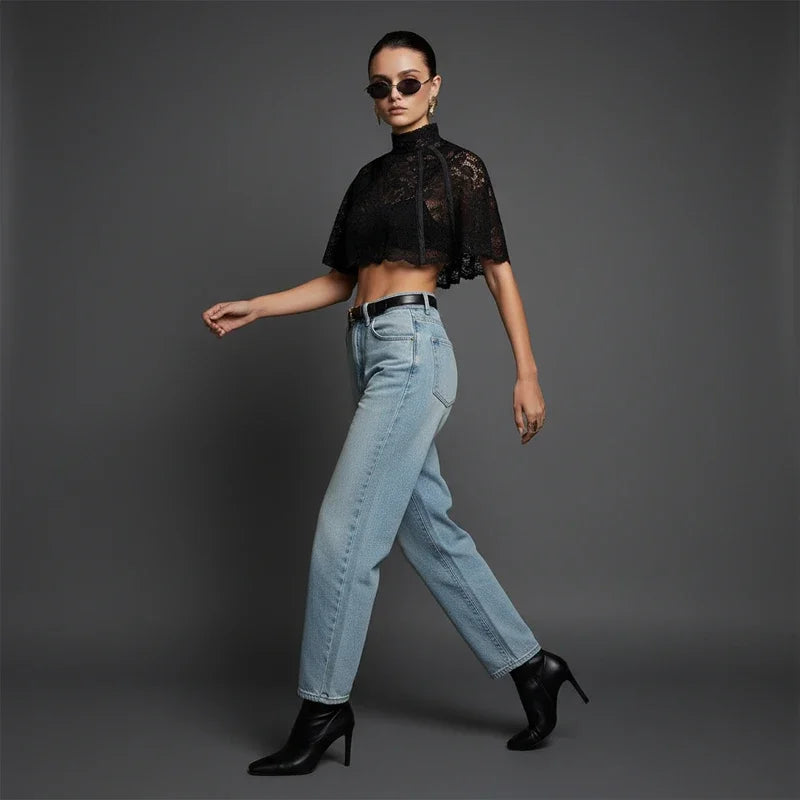 Woman wearing a black lace top, light blue jeans, and black high-heeled shoes on a gray background