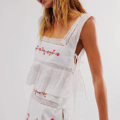 White embroidered top with floral patterns on a plain background