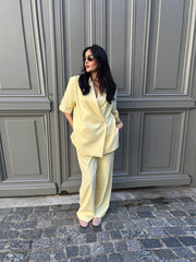 Woman in a light yellow outfit standing in front of a gray door.