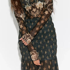 Model seated wearing smocked ruffled tiered star print sheer maxi skirt