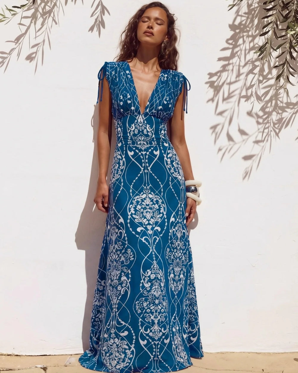 Woman wearing blue and white architectural print two-piece swimwear set with a maxi skirt.