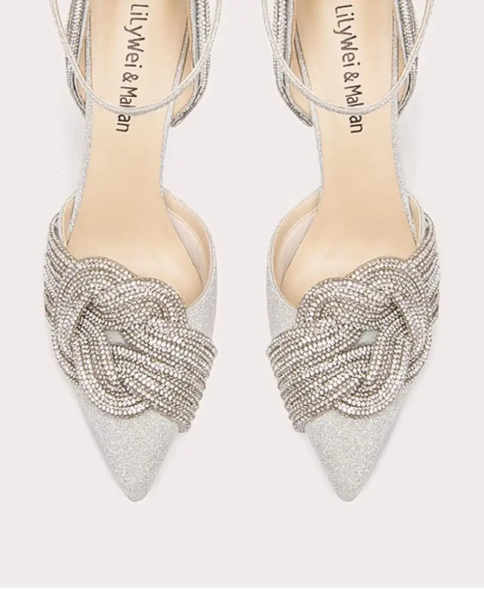 Pair of silver high-heeled shoes with intricate designs on a white background