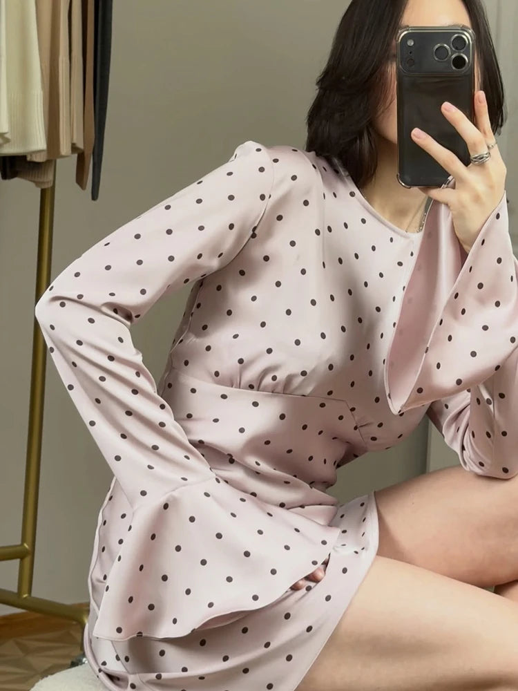 Person wearing a pink polka dot dress sitting on a chair.
