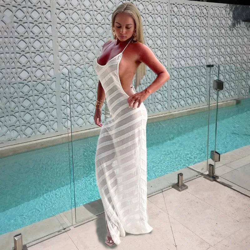 Woman in a white dress standing by a pool with decorative wall in the background