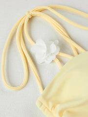 Close-up detail of floral accent on tie strap of yellow swimwear