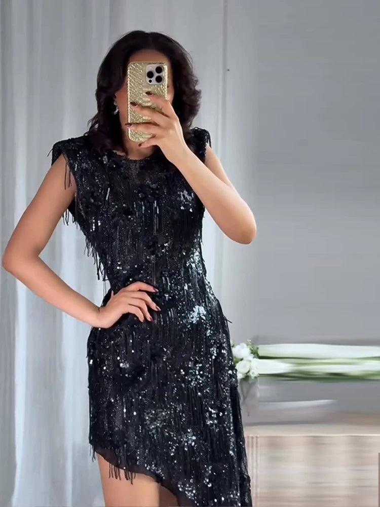 Person wearing a black sequin dress taking a mirror selfie.