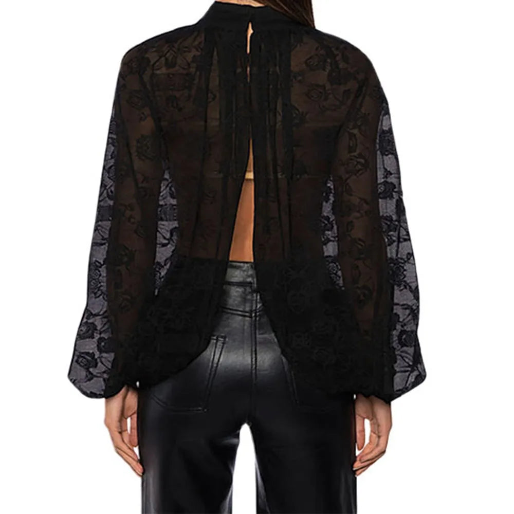 Black sheer blouse with floral patterns worn over a black leather outfit on a white background