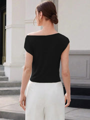 Woman wearing a black top and white pants standing in front of a classical building.