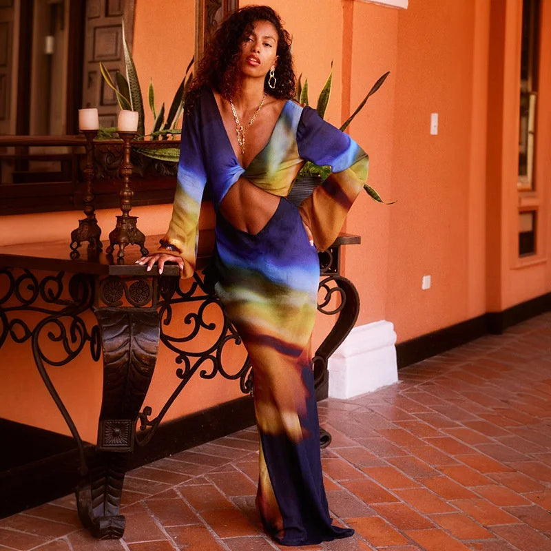 Woman in a colorful dress standing in an indoor setting with orange walls and a tiled floor.