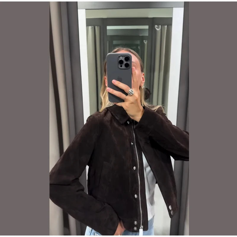 Person wearing a dark brown jacket taking a mirror selfie.