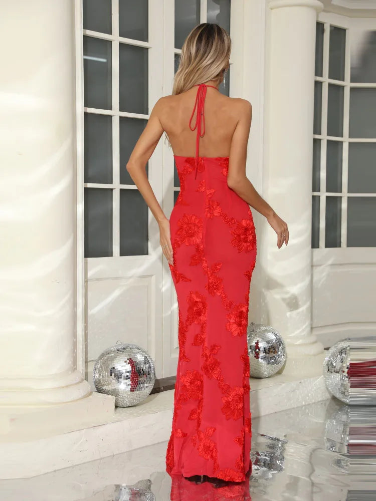 Woman wearing a red evening gown with floral details in an elegant indoor setting.
