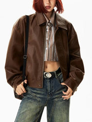 A woman wearing a brown cropped faux leather biker jacket with zipper details. Golden Atelier 3