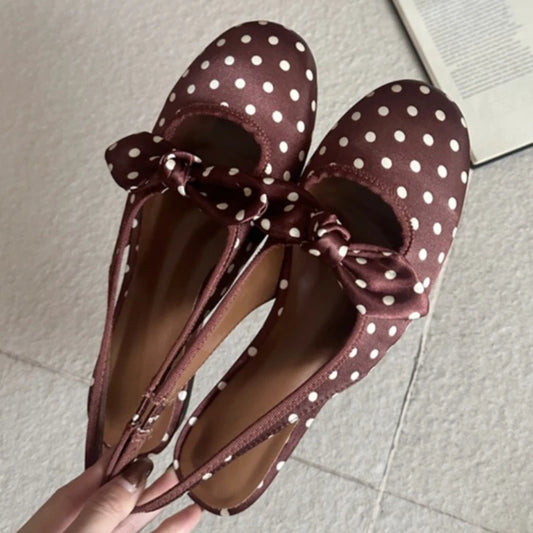 Close-up of brown polka dot slingback pumps showing bow detail.